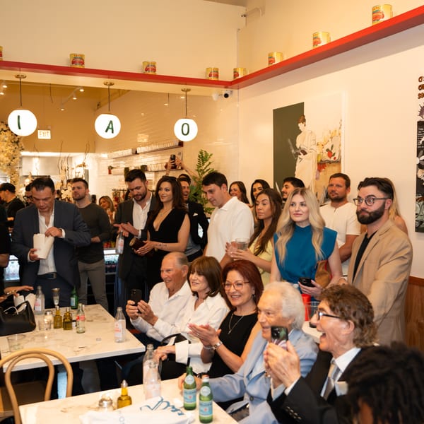 A lively crowd of people, some seated and some standing, enjoying an event in a restaurant.